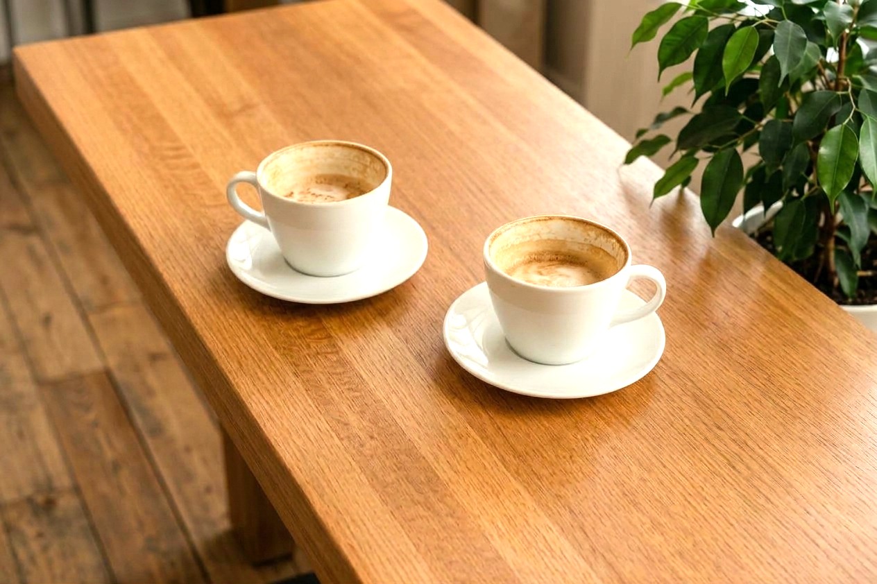 木のテーブルに少し離して置かれた2つのコーヒーカップ